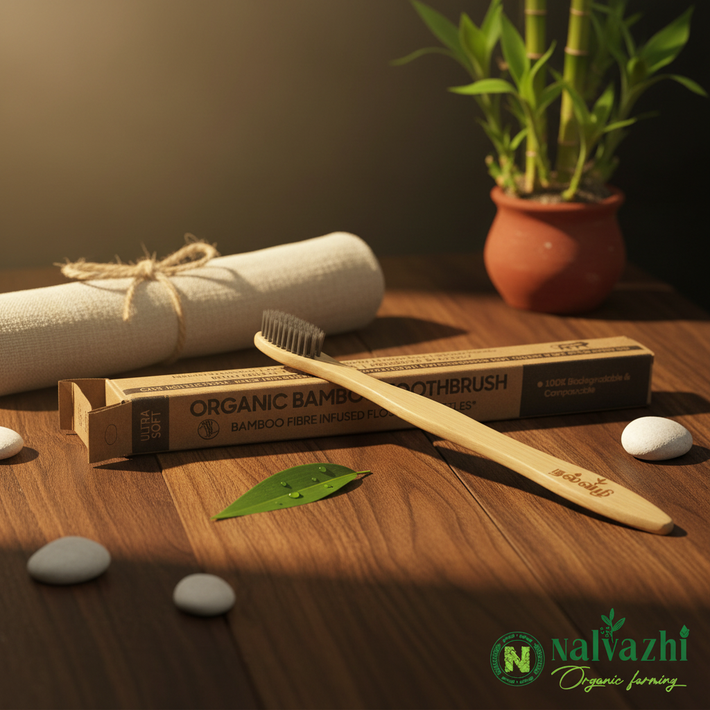 Nalvazhi Organic Bamboo Toothbrush with kraft box packaging on dark walnut wood surface with linen napkin bamboo shoots terracotta pot and white pebbles warm golden lighting
