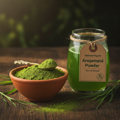Arugampul herbal powder in terracotta bowl with glass of fresh green arugampul juice and grass blades
