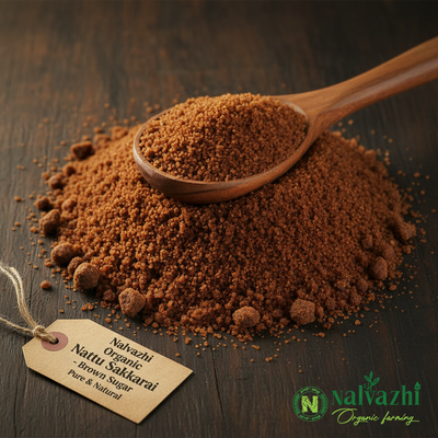 Nalvazhi Organic Nattu Sakkarai deep brown sugar granules on dark wooden surface with wooden spoon