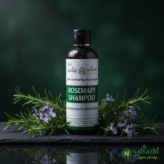 Nalvazhi Rosemary Shampoo dark bottle surrounded by fresh rosemary sprigs with purple-blue flowers on dark moody background