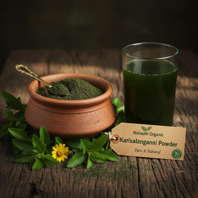 Karisalanganni herbal powder in terracotta bowl with fresh Eclipta alba plant leaves and flowers and herbal juice glass