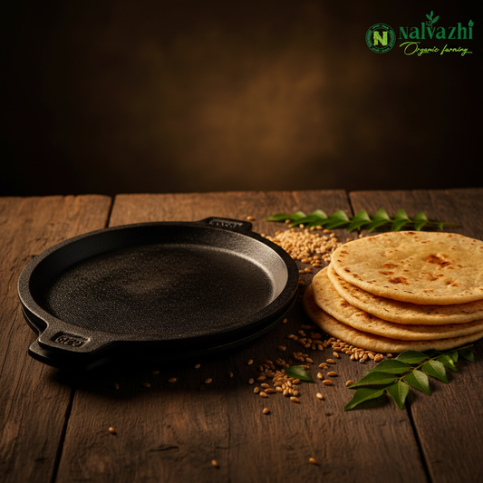 Traditional cast iron chapati tawa with freshly made chapatis, wheat grains and curry leaves on rustic wooden surface